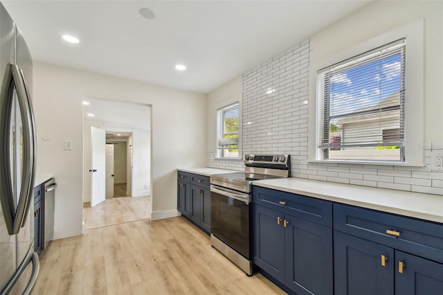 3535 16th St N, Saint Petersburg, FL 33704 - kitchen featuring appliances with stainless steel finishes, backsplash, blue cabinetry, light wood finished floors, and light countertops