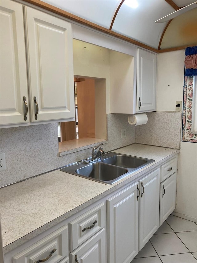 kitchen featuring light tile patterned floors, light countertops, white cabinets, and a sink