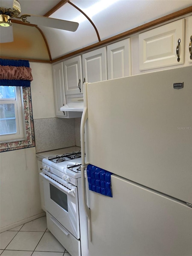 kitchen featuring under cabinet range hood, light tile patterned flooring, white appliances, and white cabinets