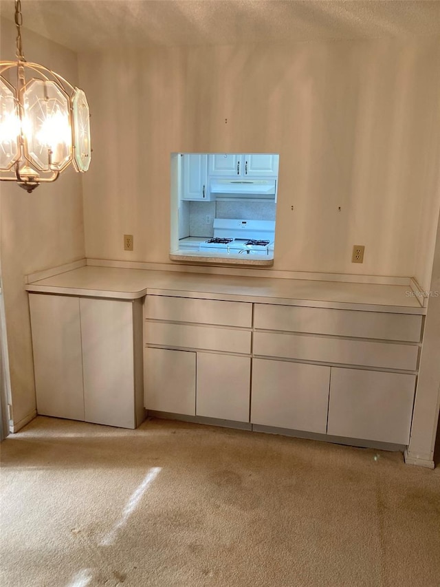 unfurnished dining area with light colored carpet, a textured ceiling, and a notable chandelier