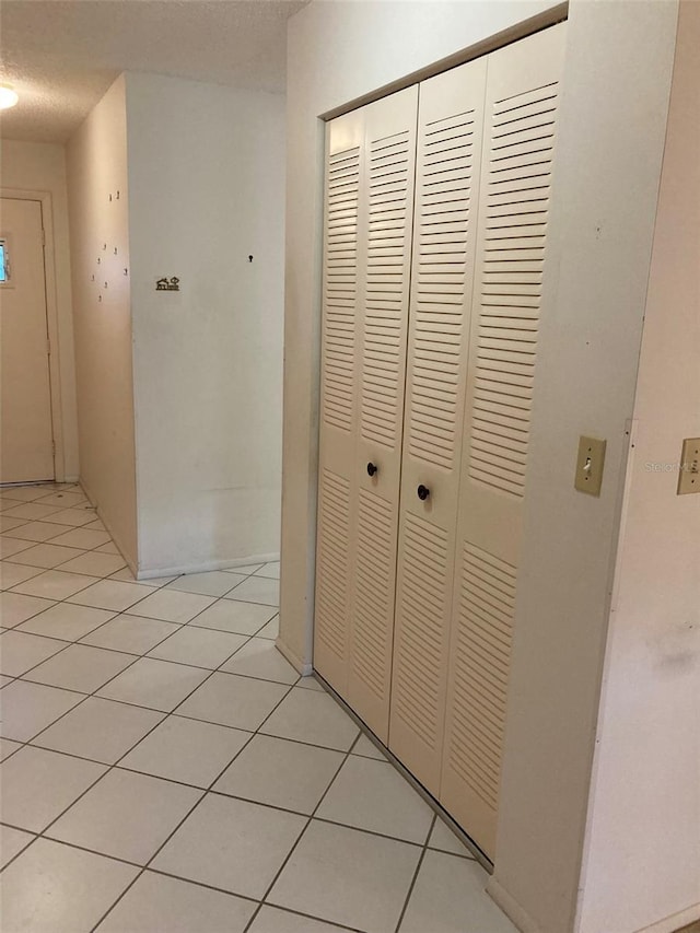 corridor featuring a textured ceiling and light tile patterned flooring