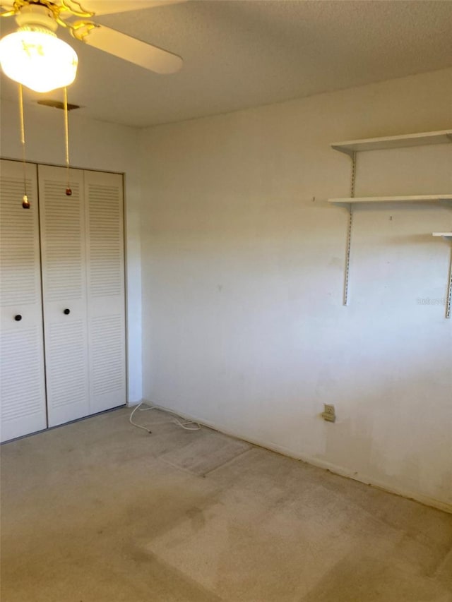 unfurnished bedroom featuring light colored carpet, a closet, and a ceiling fan