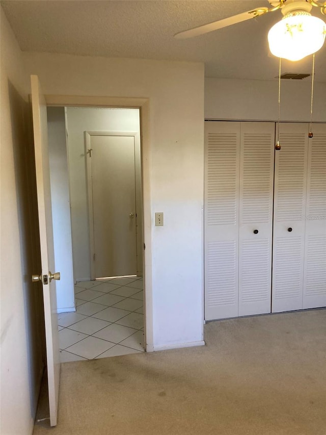 unfurnished bedroom with light carpet, a closet, and light tile patterned floors