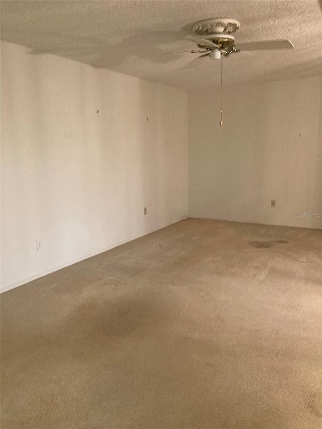 carpeted empty room featuring a ceiling fan and a textured ceiling
