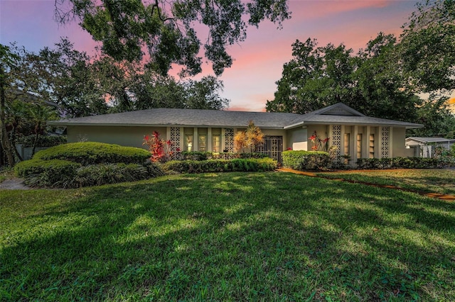 ranch-style home featuring a yard and stucco siding