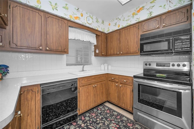 kitchen with black appliances, a sink, light countertops, wallpapered walls, and backsplash