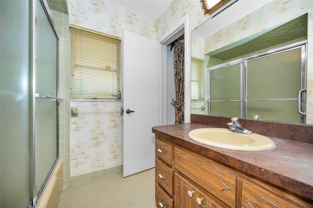 bathroom featuring wallpapered walls, tile patterned flooring, vanity, and combined bath / shower with glass door
