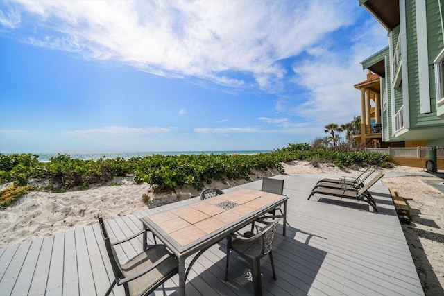 deck with outdoor dining area and a water view