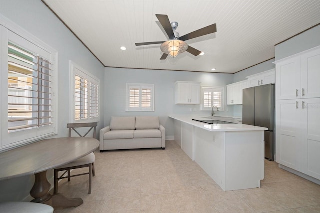kitchen featuring a sink, freestanding refrigerator, light countertops, light tile patterned floors, and white cabinets