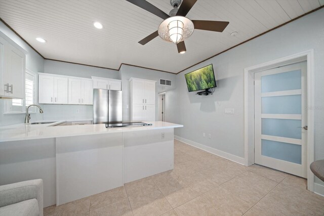 kitchen with freestanding refrigerator, visible vents, a sink, a peninsula, and light countertops