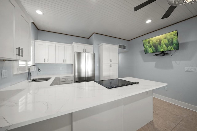 kitchen featuring freestanding refrigerator, a ceiling fan, light stone countertops, visible vents, and a sink