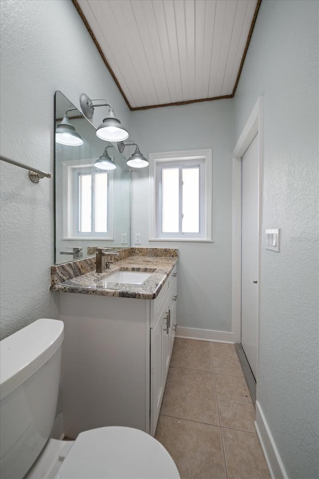 half bathroom featuring vanity, toilet, baseboards, and tile patterned floors