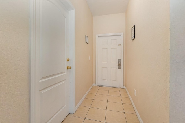 doorway with light tile patterned floors and baseboards