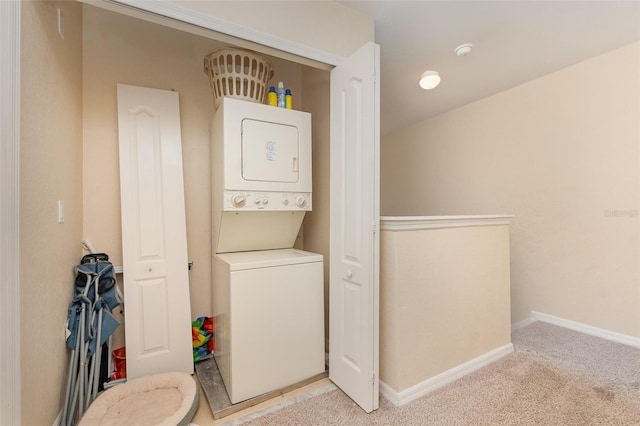 washroom featuring stacked washing machine and dryer, light carpet, and baseboards