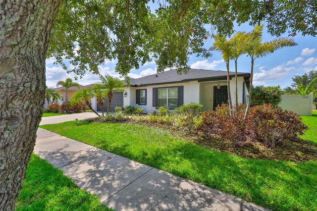 ranch-style house with a front yard, stucco siding, an attached garage, and driveway