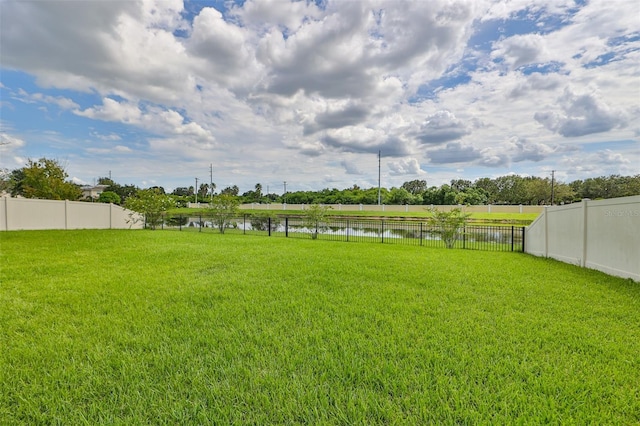 view of yard featuring a water view and a fenced backyard