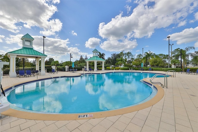 community pool with a gazebo and a patio
