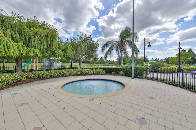 view of pool featuring playground community, a patio, a pool, and fence