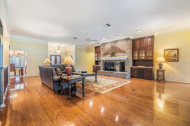 2769 St Andrews Blvd, Tarpon Springs, FL 34688 - living area with light wood-style flooring, a ceiling fan, a brick fireplace, baseboards, and ornamental molding