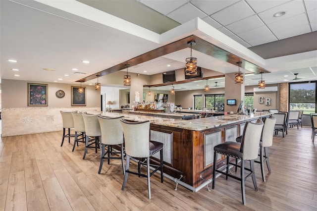 2769 St Andrews Blvd, Tarpon Springs, FL 34688 - kitchen featuring light wood-style floors, a kitchen bar, light stone counters, pendant lighting, and a large island with sink