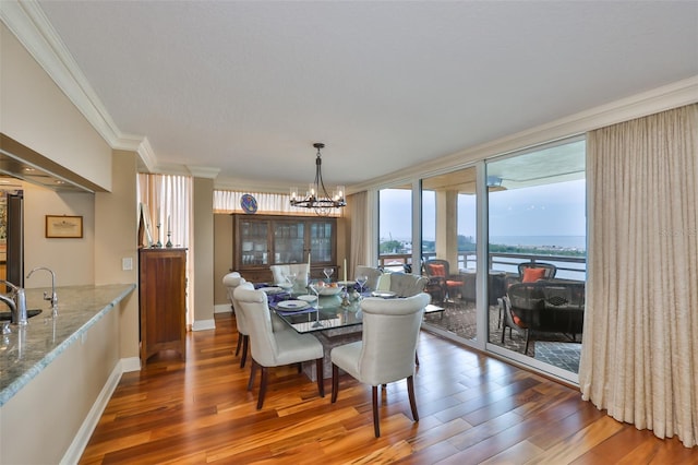 5701 Mariner St Unit 701, Tampa, FL 33609 - dining room featuring crown molding, wood finished floors, a chandelier, baseboards, and a water view