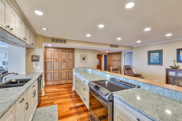 5701 Mariner St Unit 701, Tampa, FL 33609 - kitchen featuring appliances with stainless steel finishes, a sink, light wood finished floors, recessed lighting, and white cabinets