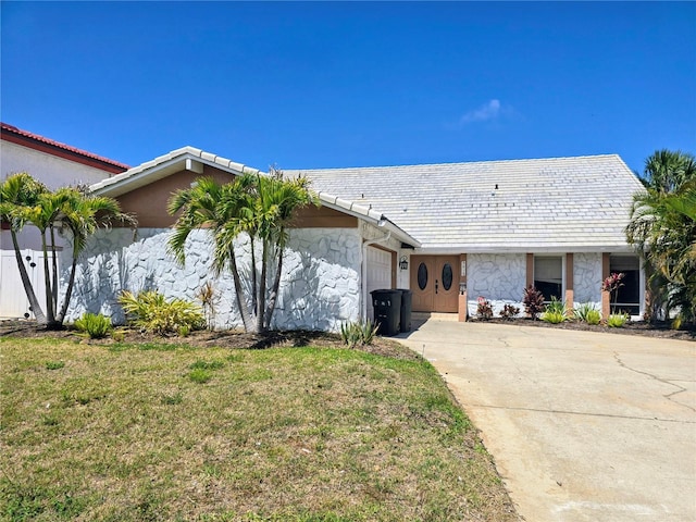 ranch-style home featuring stone siding, a garage, concrete driveway, a front yard, and stucco siding