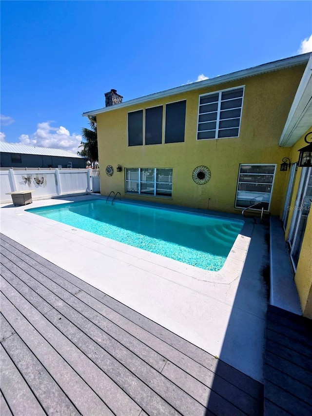 view of swimming pool featuring fence and a wooden deck