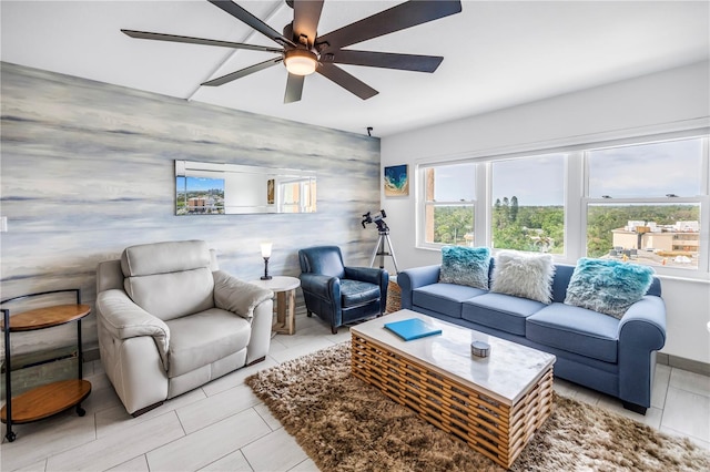 living area featuring ceiling fan, an accent wall, light tile patterned floors, and wallpapered walls