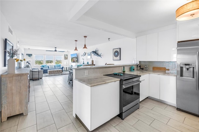 kitchen with stainless steel refrigerator with ice dispenser, electric range oven, a peninsula, white cabinets, and backsplash