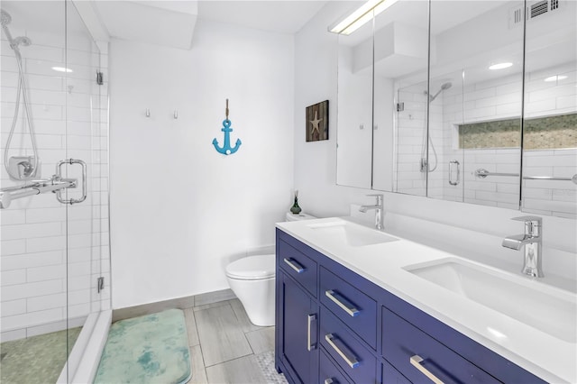 full bathroom with a stall shower, toilet, baseboards, and double vanity