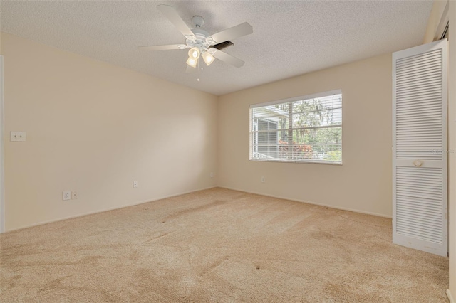 empty room with carpet floors, a ceiling fan, and a textured ceiling