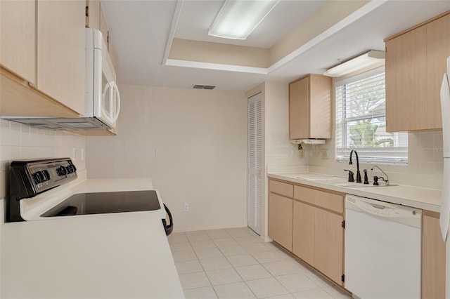kitchen with white appliances, a sink, light brown cabinets, and decorative backsplash