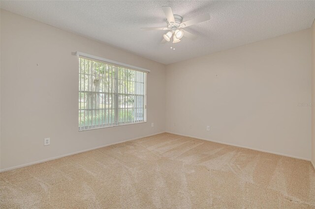 carpeted empty room with ceiling fan, baseboards, and a textured ceiling