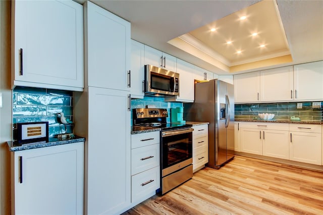 400 Island Way Unit 1709, Clearwater Beach, FL 33767 - kitchen featuring appliances with stainless steel finishes, a tray ceiling, backsplash, light wood-style flooring, and crown molding