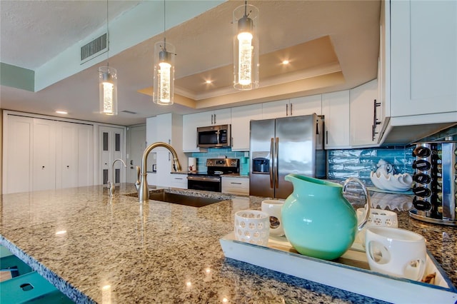 400 Island Way Unit 1709, Clearwater Beach, FL 33767 - kitchen with appliances with stainless steel finishes, a tray ceiling, tasteful backsplash, light stone countertops, and crown molding
