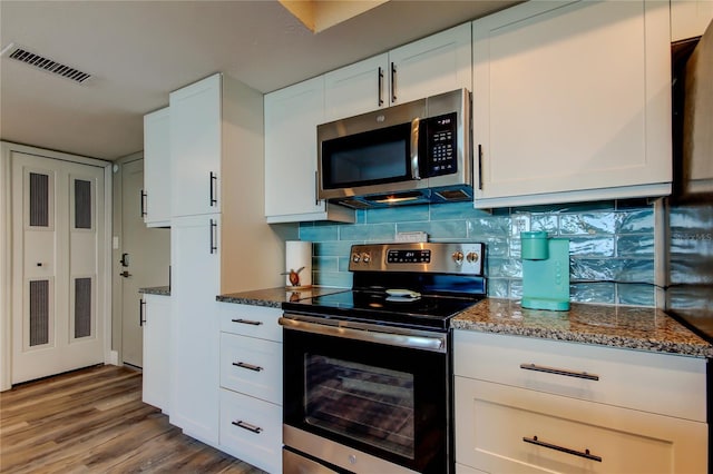 400 Island Way Unit 1709, Clearwater Beach, FL 33767 - kitchen featuring stainless steel appliances, wood finished floors, dark stone counters, white cabinets, and decorative backsplash