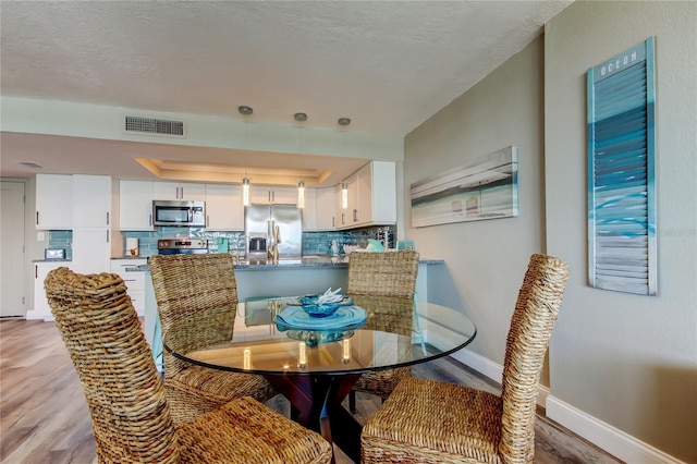400 Island Way Unit 1709, Clearwater Beach, FL 33767 - dining room with wood finished floors, baseboards, a tray ceiling, and a textured ceiling