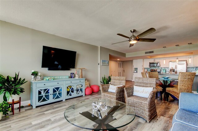400 Island Way Unit 1709, Clearwater Beach, FL 33767 - living area with light wood finished floors, a ceiling fan, a textured ceiling, and baseboards