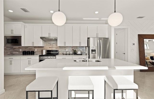 kitchen with appliances with stainless steel finishes, a sink, a kitchen island with sink, white cabinetry, and recessed lighting