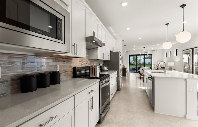 kitchen featuring stainless steel appliances, under cabinet range hood, a sink, decorative backsplash, and recessed lighting
