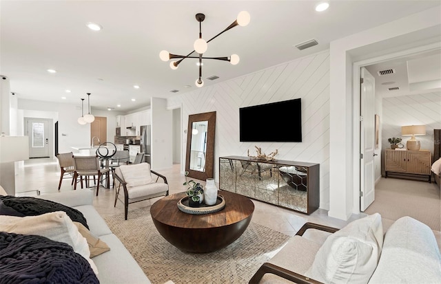 living room with an accent wall, a chandelier, recessed lighting, and wood walls