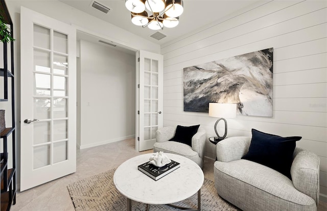 living area with french doors, wood walls, and a chandelier