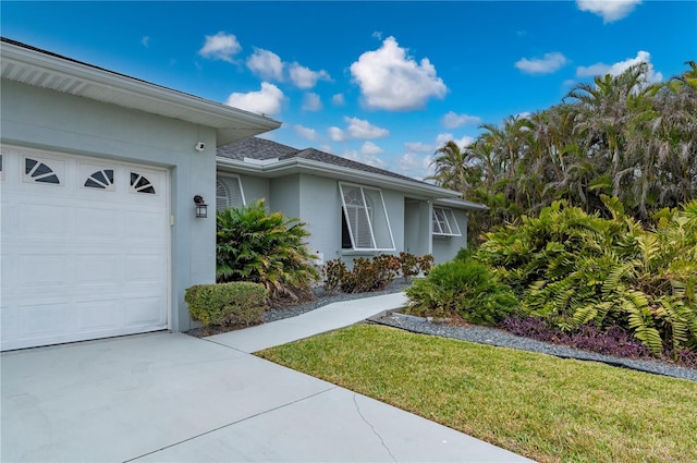 5193 Boyle Ter, Port Charlotte, FL 33981 - view of front of home with stucco siding, an attached garage, a front lawn, concrete driveway, and roof with shingles