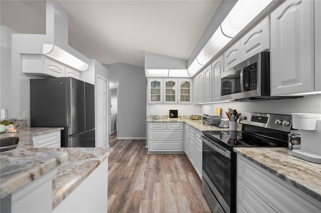5193 Boyle Ter, Port Charlotte, FL 33981 - kitchen with appliances with stainless steel finishes, vaulted ceiling, light stone counters, white cabinetry, and light wood-type flooring