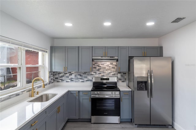 5210 S 80th St, Tampa, FL 33619 - kitchen with appliances with stainless steel finishes, a sink, under cabinet range hood, light countertops, and decorative backsplash
