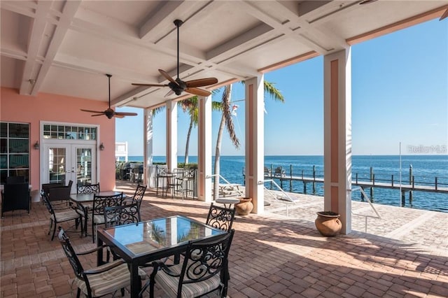 view of patio / terrace with french doors, a ceiling fan, outdoor dining space, and a water view