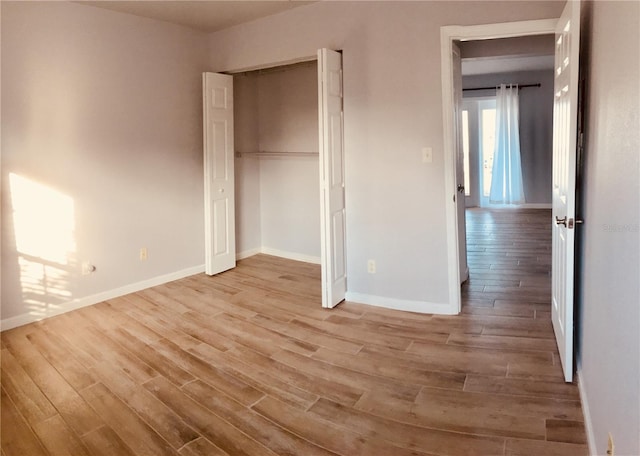 unfurnished bedroom with wood finished floors, baseboards, and a closet