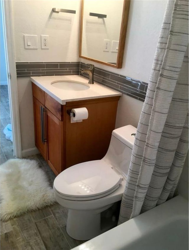 bathroom with tile walls, toilet, vanity, a shower with curtain, and a wainscoted wall
