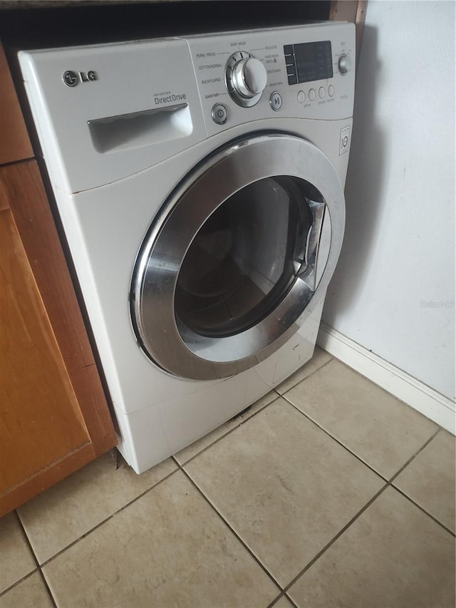 laundry area featuring baseboards, washer / clothes dryer, laundry area, and light tile patterned flooring